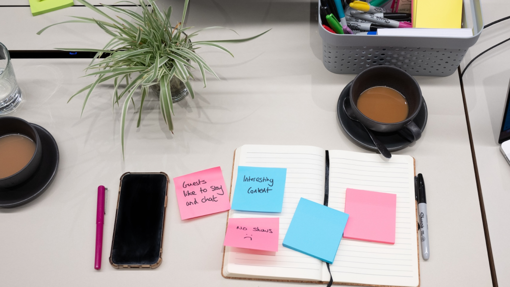 Aerial view of a desk with notebooks, colorful sticky notes, and a cup of tea