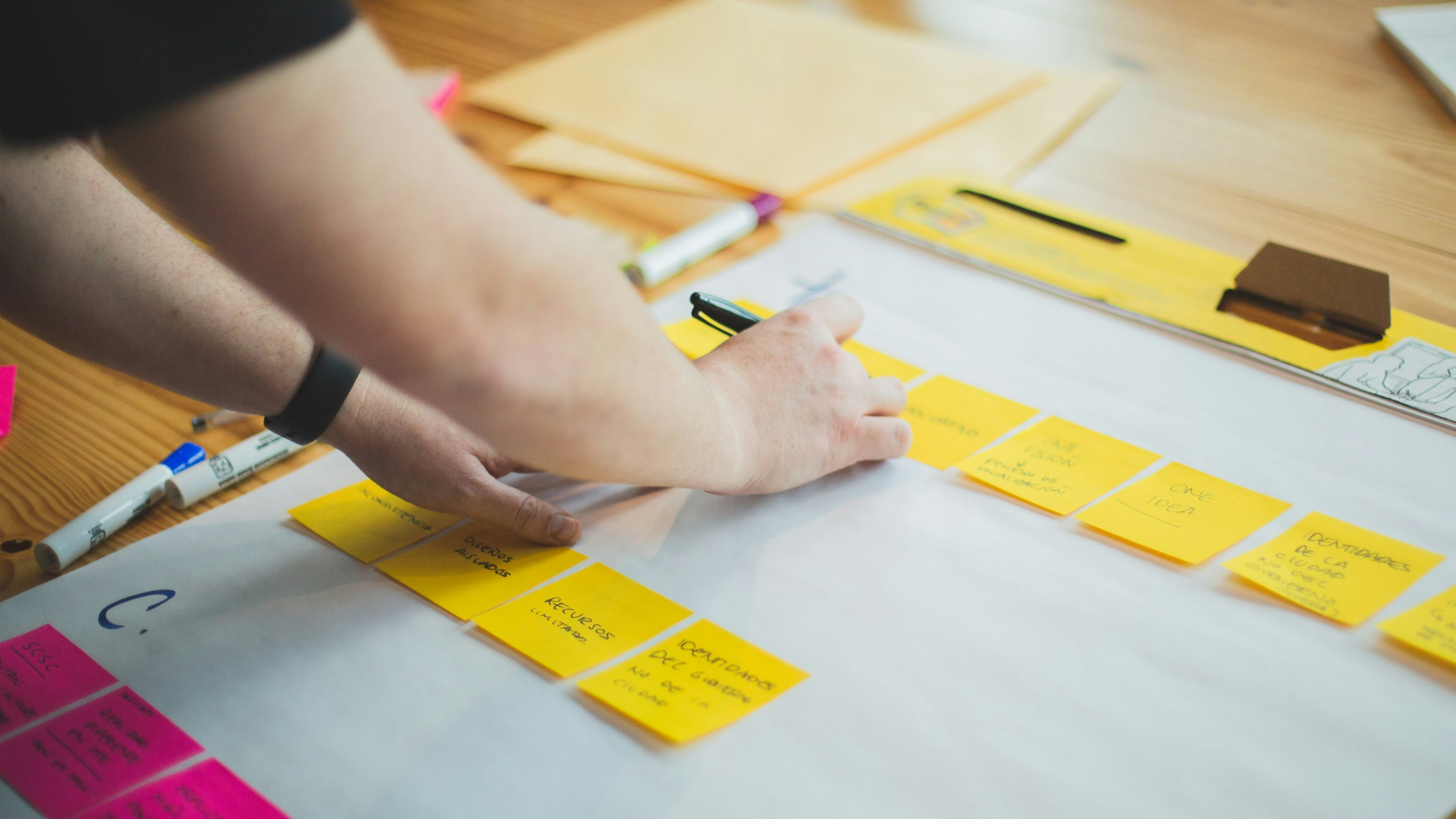 Person adding notes to post-it notes during a service design workshop session