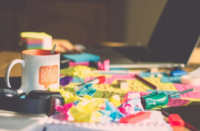 Cluttered desk with post-it notes and office items