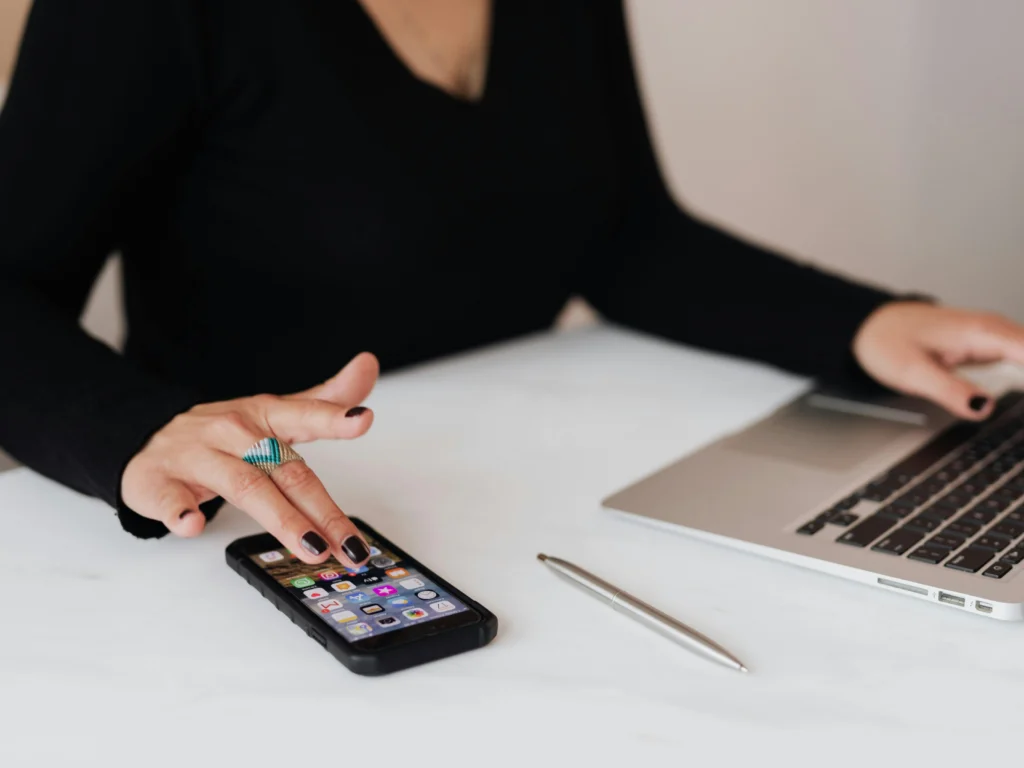 Woman using a mobile phone and laptop while sitting at a desk