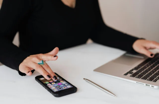 Woman using a mobile phone and laptop while sitting at a desk